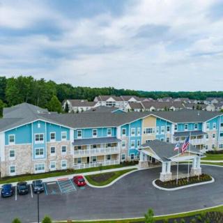 A modern residential apartment complex with a parking lot and surrounding greenery.