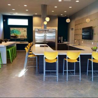 A modern kitchen with vibrant yellow chairs and stainless steel appliances.