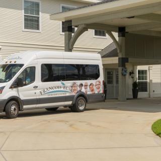 A white van parked under an awning in front of a building.