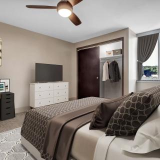 A cozy bedroom with modern furnishings, including a bed, dresser, and ceiling fan.