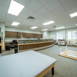 A spacious therapy room equipped with various rehabilitation tools and exercise equipment.