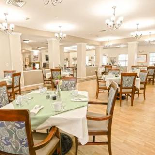 An elegantly designed dining area with neatly arranged tables and chairs, illuminated by chandeliers.