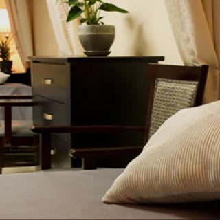 A cozy bedroom setting with a focus on a pillow and a plant in the background.