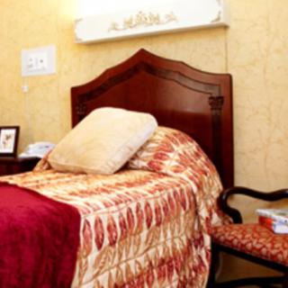 A cozy bedroom with a wooden bedframe, patterned bedding, and a plush chair beside it.