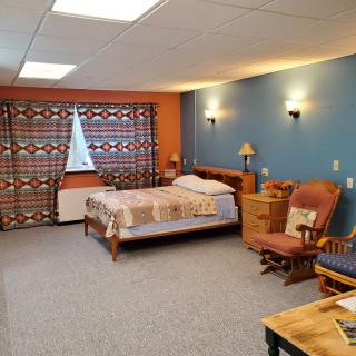 A cozy bedroom with a bed, chairs, and warm lighting.