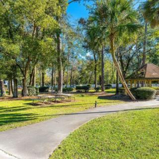 A sunny park with trees, a pathway, and a gazebo.