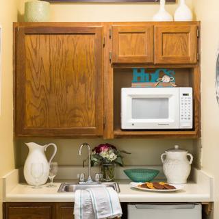 A small kitchen area with wooden cabinets, a microwave, and decorative elements on the countertop.