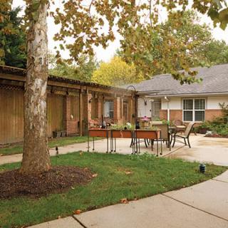 A serene courtyard with outdoor furniture surrounded by trees and a house exterior.