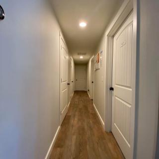 A well-lit hallway with several doors and wooden flooring.