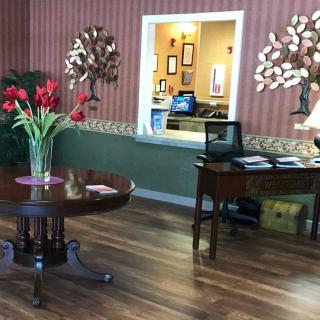 A cozy lobby area with a round table adorned with flowers, featuring warm decor and a wooden floor.