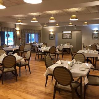 An elegant dining room with neatly arranged tables and chairs, featuring warm lighting and tasteful decor.