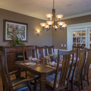 A well-appointed dining room featuring a wooden table and chairs, with a chandelier and wall art enhancing the warm ambiance.
