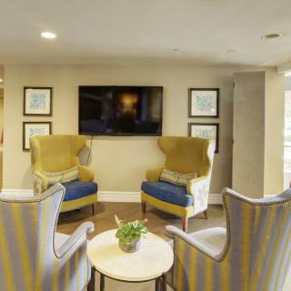 A cozy living room setup with two armchairs, a TV on the wall, and decorative artwork.