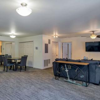 A spacious open-floor living and dining area with modern furnishings and a ceiling fan.
