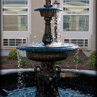 An ornamental outdoor fountain with cascading water in a garden setting.