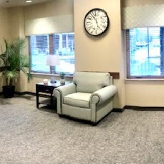 A cozy waiting room with a comfortable chair and a large clock on the wall.