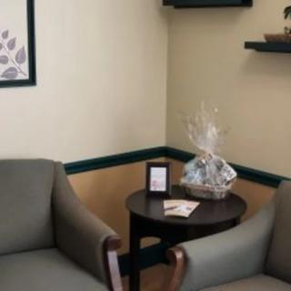 A cozy waiting room with two chairs and a small table displaying a gift basket.