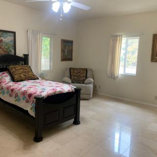 A cozy bedroom with a single bed, armchair, and decorated with paintings.