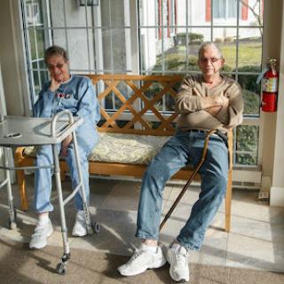 Two seniors relaxing together in a sunlit indoor setting.