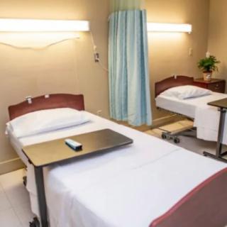A clean hospital room with two beds separated by a curtain.