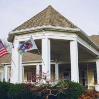 A suburban house with a porch and flags displayed.