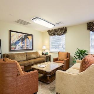 A cozy living room with couches, armchairs, a central table, and decorative elements.