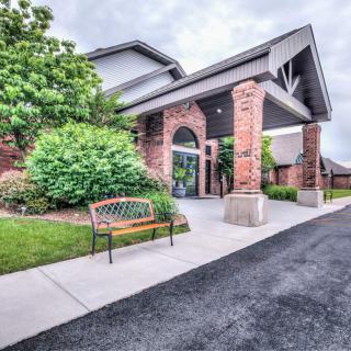 A brick building entrance with a bench and landscaped greenery.
