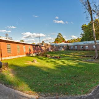 A scenic view of a building complex surrounded by lush green grass and a clear blue sky.