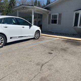 A white car parked next to a building with a wooden ramp extending towards it.