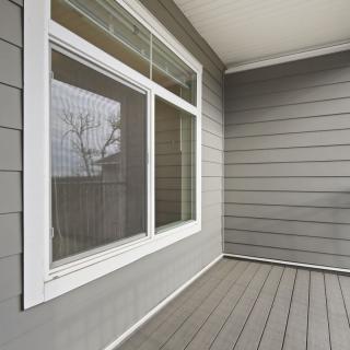 A clean and modern patio area with a large window and gray siding.