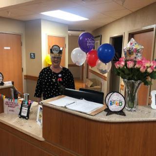 A cheerful reception area decorated for a special occasion, featuring balloons and flowers.