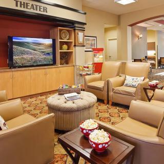 A cozy home theater with comfortable seating, a TV screen, and popcorn ready for a movie night.