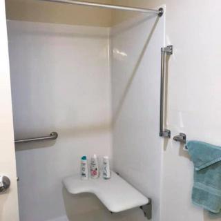 An accessible bathroom shower with a seat and handrails.
