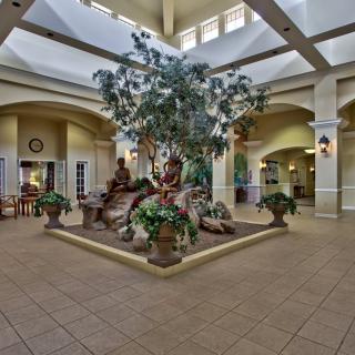 A spacious indoor atrium with a central fountain surrounded by plants, showcasing elegant architecture and interior design.