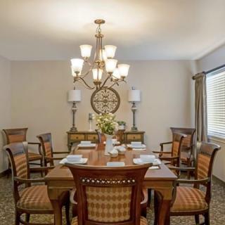 A well-decorated dining room featuring a large wooden table, elegant chairs, and a central chandelier.