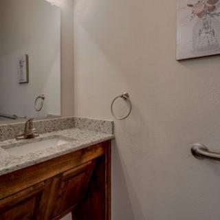 A bathroom featuring a sink with a marble countertop, mirror, towel ring, and wall artwork.
