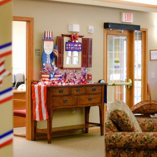 A living room decorated with American flags and patriotic themes, featuring a wooden sideboard and comfortable seating.