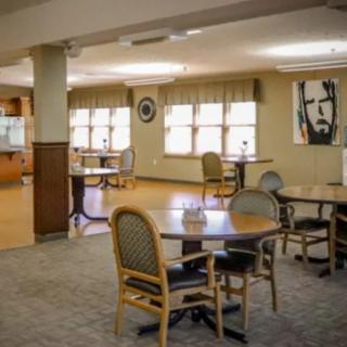 A spacious dining area with multiple tables and chairs, featuring large windows and decorated walls.