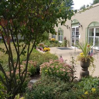 A tranquil garden area featuring lush plants and flowers, accompanied by elegant architecture.