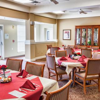 An elegantly set dining room with red tablecloths and neatly arranged chairs.