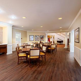 A well-lit dining area with wooden floors and elegantly arranged tables and chairs.