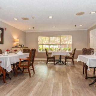 A cozy dining room with elegantly set tables and chairs, featuring a large window allowing natural light to fill the space.