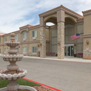 A modern hotel building with a fountain in front and an American flag displayed.