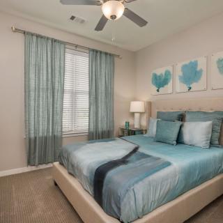A modern bedroom with a blue color scheme, featuring stylish decor and artwork.