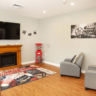 A cozy living room featuring a television, a fireplace, comfortable armchairs, and decorative wall art.