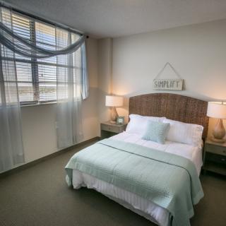 A cozy bedroom with soft pastel decor and natural lighting.