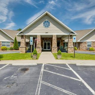 A building with a prominent entrance and parking area on a clear day.