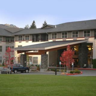 A modern building entrance with a landscaped area and parked car.