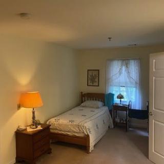 Cozy bedroom with a single bed, nightstand, and window with curtains.