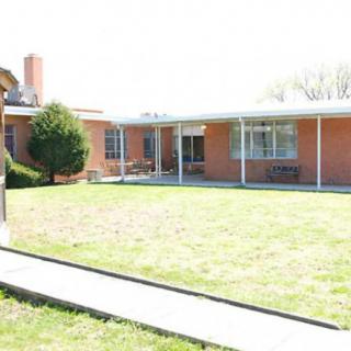 A brick house with a well-maintained lawn and covered porch area.